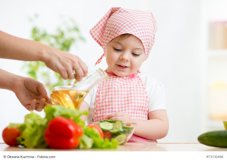 Kleines Mädchen hilft der Mutter beim Zubereiten von Salat