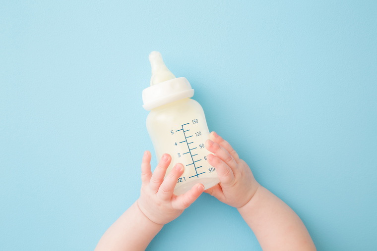 Kleinkind mit Milchflasche in der Hand
