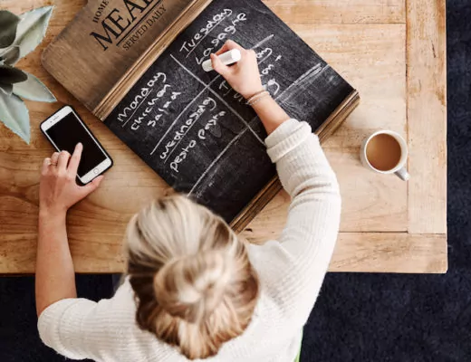 Frau erstellt einen Wochenplan fürs Essen auf einer Tafel