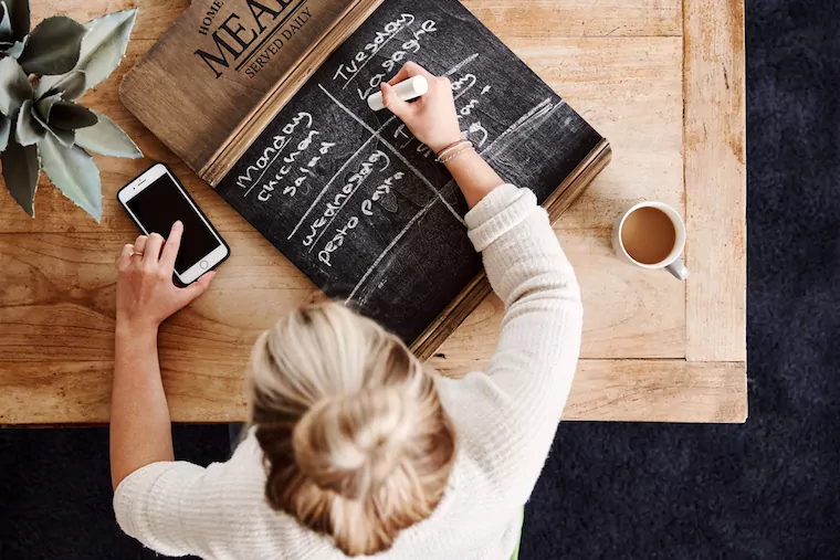 Frau erstellt einen Wochenplan fürs Essen auf einer Tafel