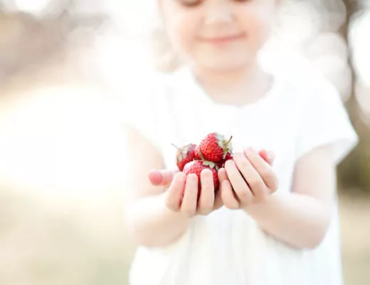 Mädchen mit einer Handvoll Erdbeeren