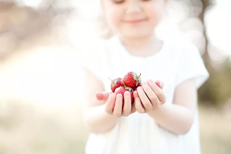 Mädchen mit einer Handvoll Erdbeeren