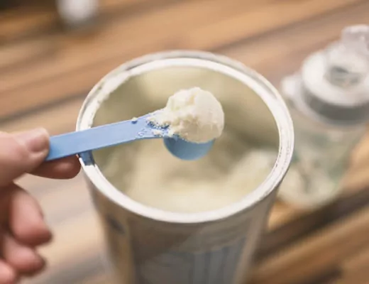 Milchpulver fürs Baby wird mit einem Dosierlöffel aus der Packung genommen.