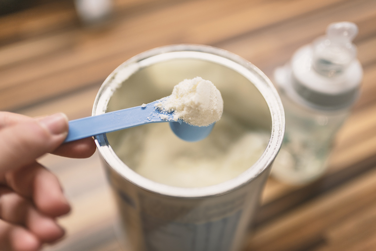 Milchpulver fürs Baby wird mit einem Dosierlöffel aus der Packung genommen.