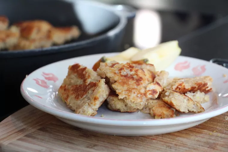 Kaiserschmarrn mit Cuscous auf einem Teller mit Apfelschnitzen.