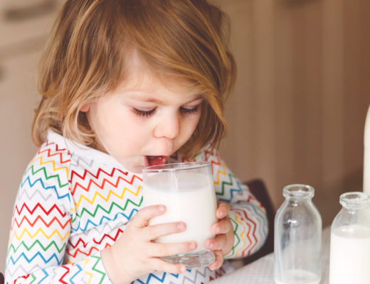 Kleines Mädchen trinkt ein Glas Milch.