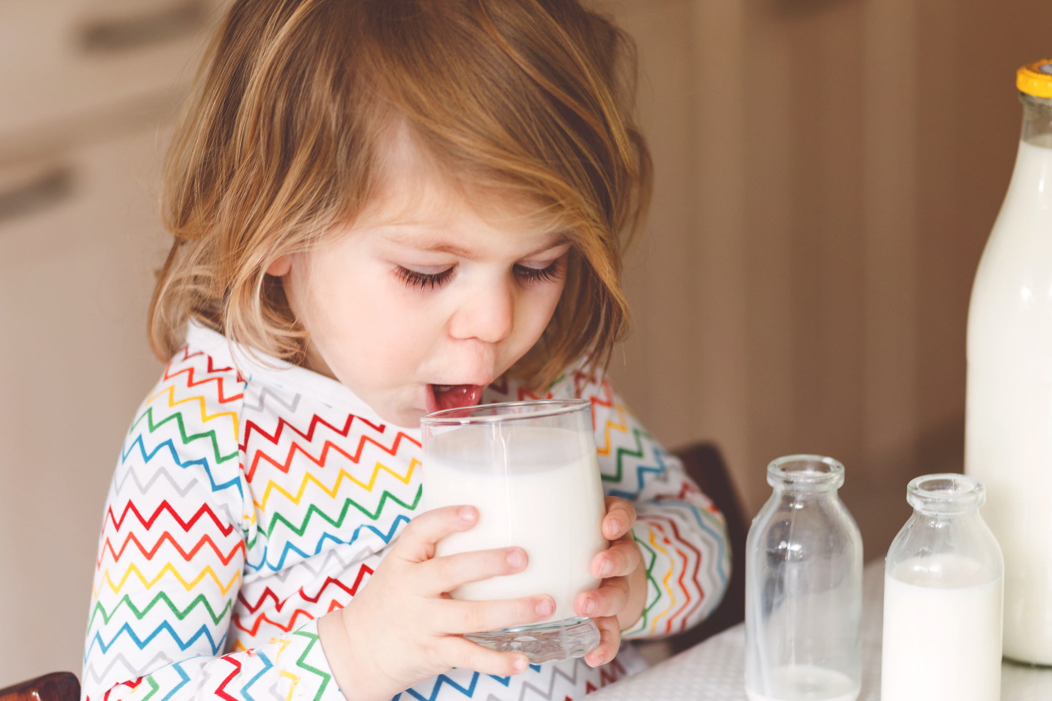Kleines Mädchen trinkt ein Glas Milch.