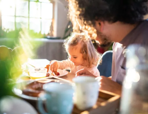 Familie sitzt gemeinsam am Tisch und isst.