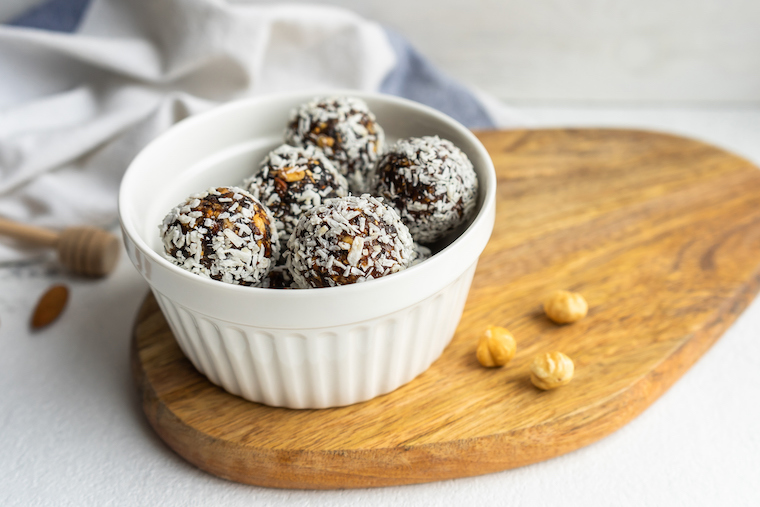 Energy Balls mit Kokosraspeln in einer weißen Schale
