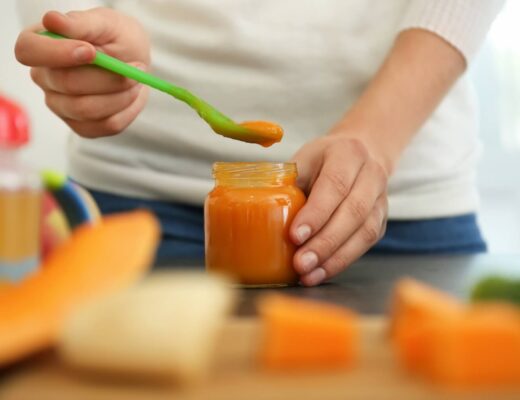 Frau bereitet ein Gläschen mit Babybrei zu.